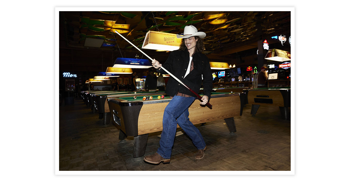 A man wearing Jackpot 11” Western in brown holding a pool stick, playing pool.